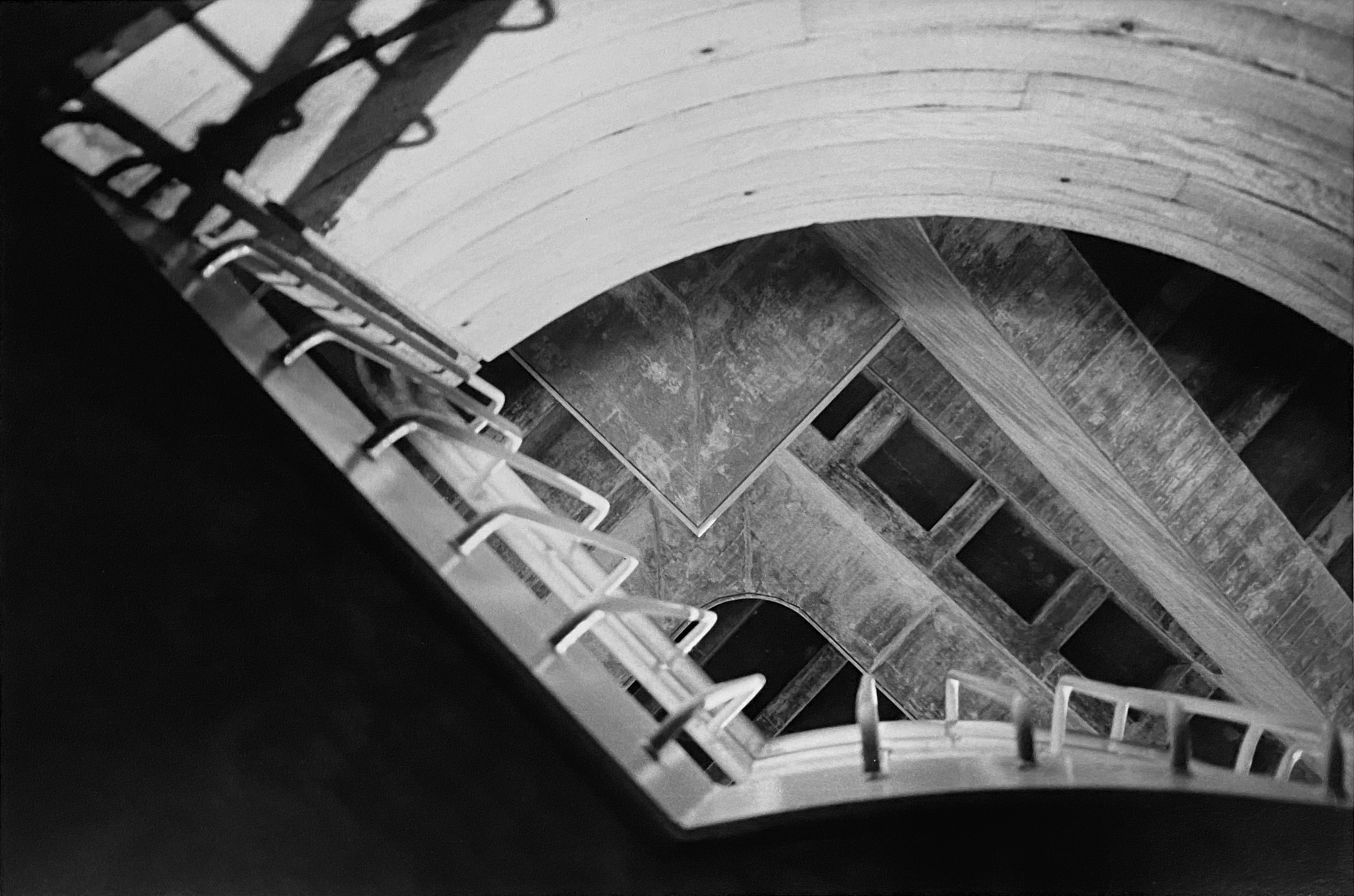 A black-and-white photograph of a building taken from an upward viewing angle. The curved roofline forms a fan-shaped outline.